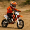 Kind op een crossmotor in actie, rijdend op een KTM 65SX in een zandbaan, met helm en volledige bescherming