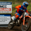 Motocrossrijder scheurt door de modder op het circuit van MCC Holland in Gouda, met nieuwsupdate van Motocrossplanet op de achtergrond