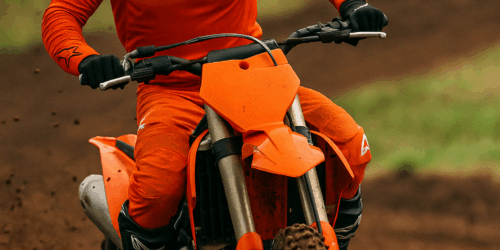 Een motorcrosser met Arai crosshelm en volledige Alpinestars uitrusting in actie op een modderige baan