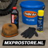 Een vies luchtfilter naast een emmer met cleaner, luchtfilterolie en onderhoudshandschoenen, klaar voor schoonmaak in een crossgarage