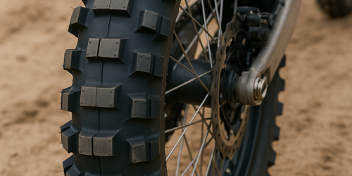 Close-up van een nieuwe buitenband voor een crossmotor met grof profiel op een zanderige ondergrond