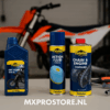 Putoline motorolie, luchtfilterolie en kettingreiniger netjes opgesteld in een crossgarage naast een motor met gereedschap