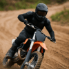 Een motorcrosser in volledig gear, inclusief zwarte bodyprotector en helm, rijdt door een bocht op een zanderig circuit