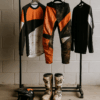 Motorcross kleding hangt te drogen aan een rek na een modderige rit, met helm, laarzen en handschoenen netjes uitgespreid in een garage