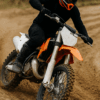 Een motorcrosser in actie op een zanderige baan, met duidelijke focus op zijn zwarte kniebeschermers tijdens het nemen van een bocht