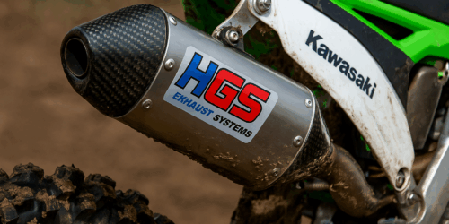 Close-up van een HGS uitlaat met carbon eindkap gemonteerd op een Kawasaki crossmotor tijdens een modderige motorcross training