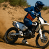 Een motocrossrijder in actie op een zandbaan, volledig uitgerust met een Alpinestars Tech 10 laars, crosshelm en HGS uitlaat