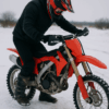 Motocrosser start zijn crossmotor op een besneeuwde ondergrond in winterse omstandigheden